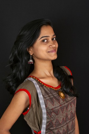 Happy young Indian woman smiling against black background, Pune, India