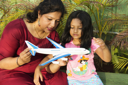 Mother showing her daughter a toy airplane while little girl observing it carefully, Puneの写真素材