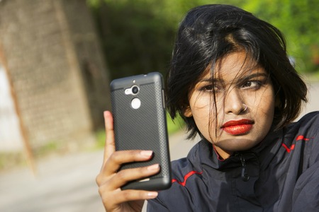 Close-up of young Indian girl with short hair wearing nose ring taking selfie, Puneの写真素材