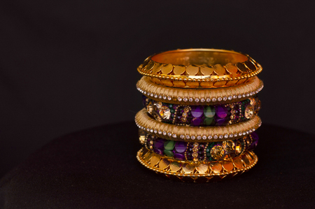 Artificial golden and colored bangles close up on a black backgroundの写真素材