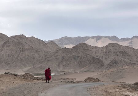 Monk walking with mountain backdrop at Ladakh, Indiaの写真素材