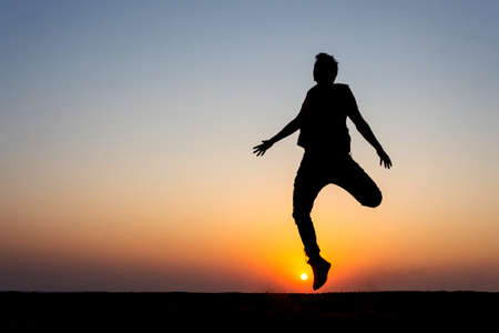 10 Nov 2020 Thar desert, Jaisalmer, Rajasthan, India. Silouette  of a boy jumping on sand while sun...