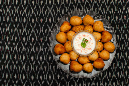 Dahi Wada, famous Indian street food or snacks in transparent colored plate on Black background