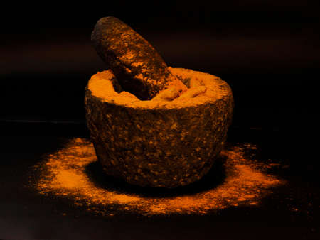 Turmeric in a stone grinder, Curcuma longa of the ginger family, Zingiberaceaeの写真素材