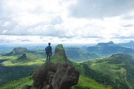 Man standing on the rock enjoying the beautiful view of Sahyadri mountains, Dhodap fort, Nashik, Maharashtra, India.のeditorial素材
