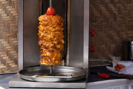 Shawarma an Arab dish with meat cut into thin slices stacked in a cone-like shape and roasted on a...