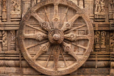 Chariot wheel with eight spokes with a central medallion. The medallions on the wheel spokes are richly carved depicting numerous deities and erotic and amorous figures in various poses. Konark Sun Temple, Orissa India. 13th Century AD.の写真素材