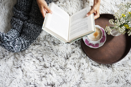 legs of girl in warm woolen socks and a book, winter morning at homeの写真素材