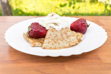 pancakes with strawberries and cream on the table