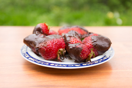 red strawberries in chocolate on a plateの写真素材