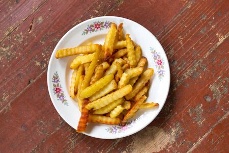French fries on a plate on wooden background