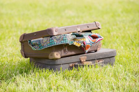 two old suitcase with clothes on grassの写真素材