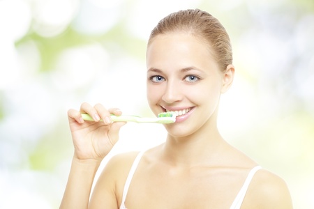 Girl brushing teeth on a light backgroundの写真素材