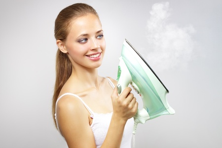 Smiling girl with iron on gray backgroundの写真素材