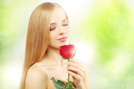beautiful girl with red rose on a green backgroundの写真素材
