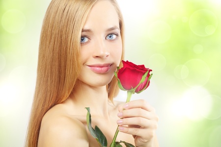 beautiful girl with red rose on a green backgroundの写真素材