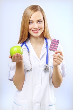 nurse holding an apple and pills on a blue backgroundの写真素材