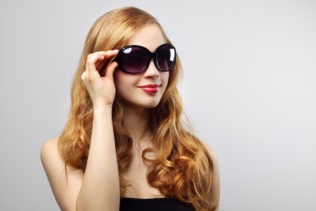 Fashionable lady wearing sunglasses on gray backgroundの写真素材