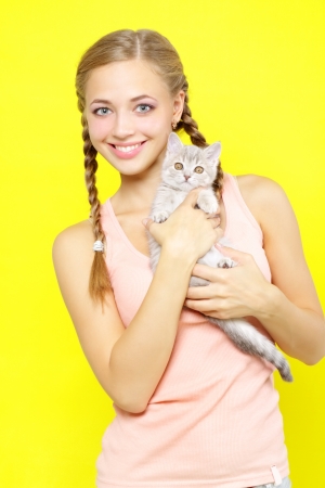 Smiling girl with Scottish Straight on yellow backgroundの写真素材