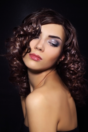 Sexy young woman with curly hair on black backgroundの写真素材