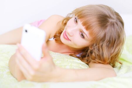 Girl with a mobile phone  on light backgroundの写真素材