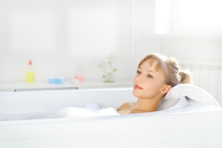 girl relaxing in bathtub on light backgroundの写真素材