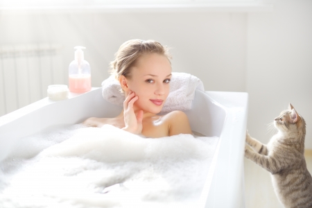 Attractive girl relaxing in bath on light backgroundの写真素材