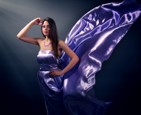 Beautiful girl in violet long dress on black backgroundの写真素材