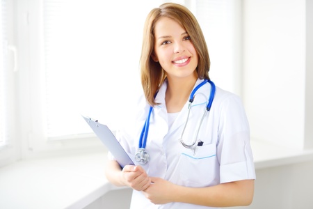 Portrait of a happy female doctor on light backgroundの写真素材