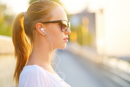 Teenage girl listening to music. background of the streetの写真素材