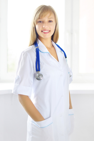 Portrait of a happy female doctor on light backgroundの写真素材