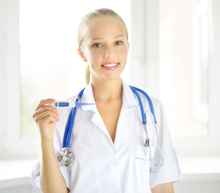 Female doctor with digital thermometer on light backgroundの写真素材
