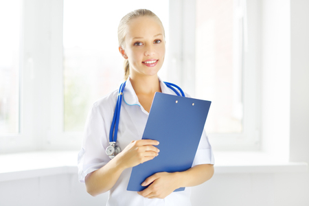 female doctor holding a notepad on light backgroundの写真素材