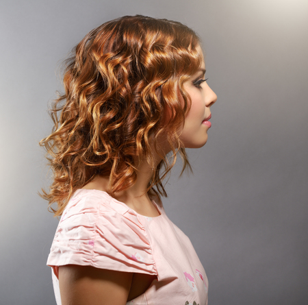 Pretty girl with short curly hair on light backgroundの写真素材