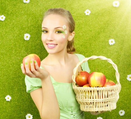 Attractive girl with a basket of apples on green の写真素材