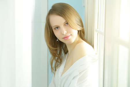 Attractive girl at the window. light backgroundの写真素材