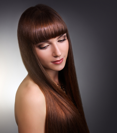 Beautiful girl with long straight hair on gray backgroundの写真素材