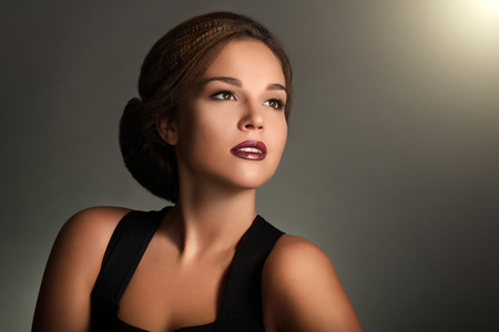 Young woman with beautiful makeup and retro hairstyle on gray backgroundの写真素材