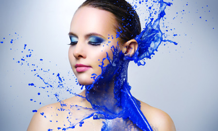 Beautiful girl and blue paint splashes on light background