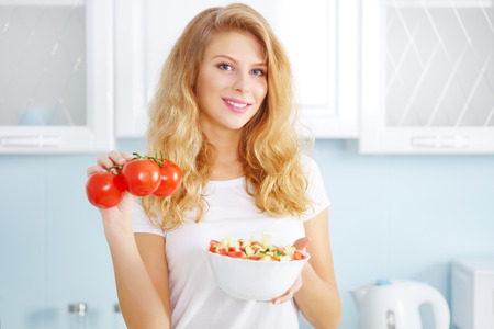 Beautiful young woman with fresh salad on a light backgroundの写真素材
