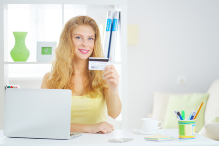 Young business woman with a credit card on a light backgroundの写真素材