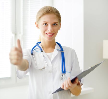 Young doctor showing thumbs up  light backgroundの写真素材