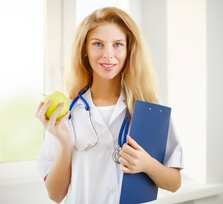 female doctor with apple on a light backgroundの写真素材