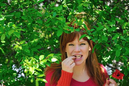 redhaired beautiful girl eats green plumの写真素材