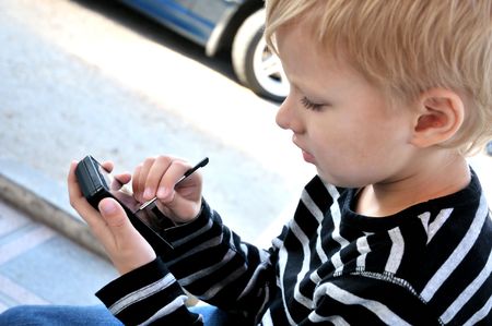 little boy using smartphone with stylusの写真素材