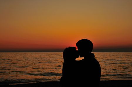 kissing couple on the beach with little peace of sunの写真素材