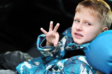 boy in the car-seat showing sign ok