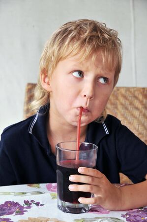 funy little boy drinking cherry juiceの写真素材
