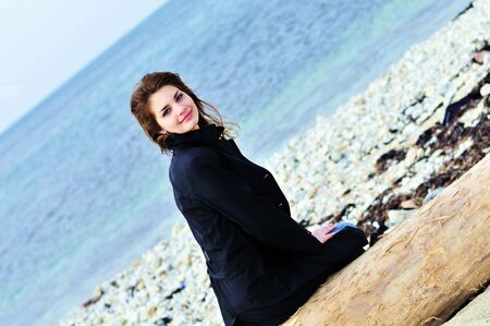 girl on the beach sitting on the  logの写真素材