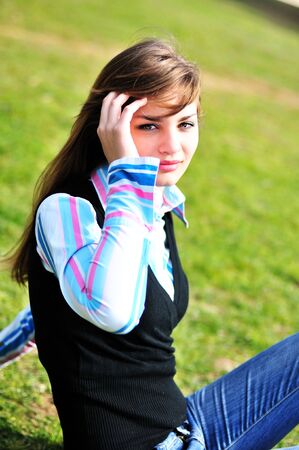 beautiful teen girl sitting on the grassの写真素材